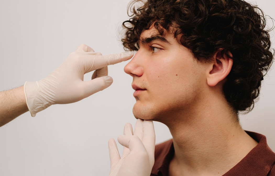 Rhinoplasty consultation for man before plastic surgery to correct the nose size and shape. Rhinoplasty reshaping nose and septoplasty. ENT doctor touching nose of male patient before rhinoplasty