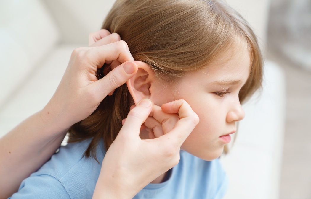 a little girl complains of pain in her ear and her mother examines it. children's diseases. corks in the ears and otitis. home remedies and medicines to treat children.