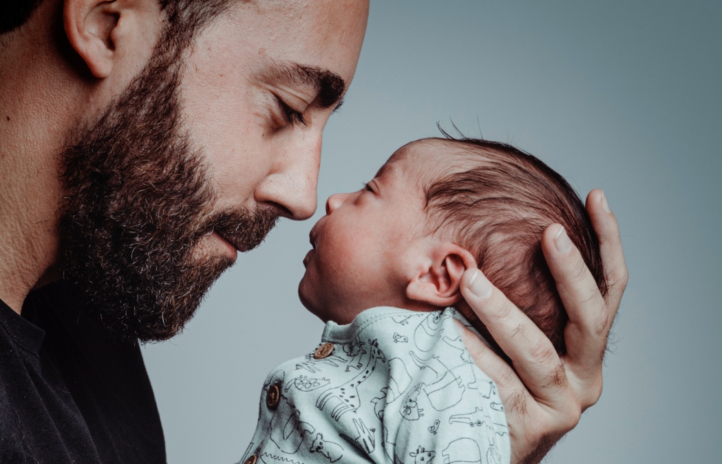 portrait of man looking at his newborn son with loving expression