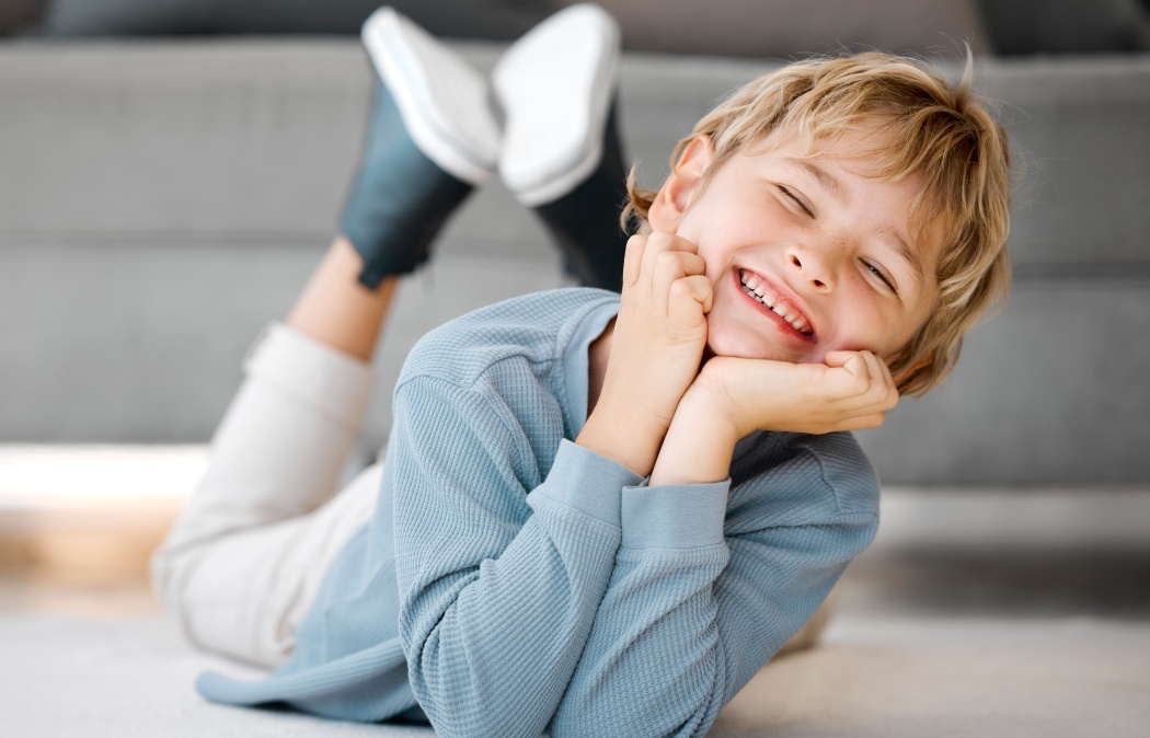 Happy kid, boy portrait and relax in home for security, weekend fun or chill in living room. Smile, young child or excited on floor for dental care, development or healthy teeth for growth in morning